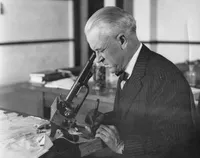 Robert A. Millikan looking through microscope